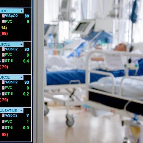 A monitor in an ICU with a patient in the background