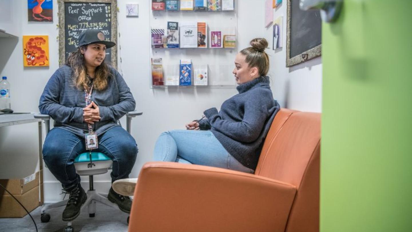 Two people seated and talking in a room