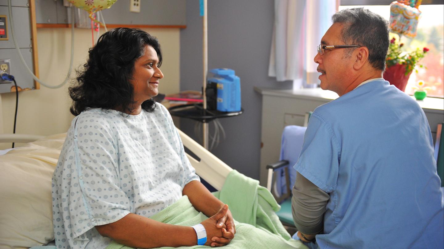 Patient sitting on a hospital bed and talking to a doctor