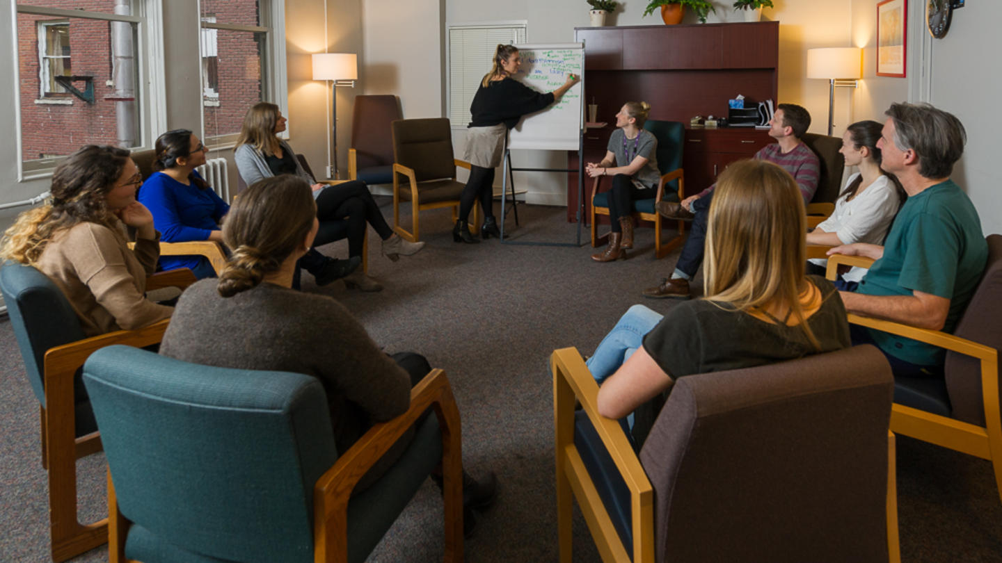 A group of people are seated in chairs arranged in a circle