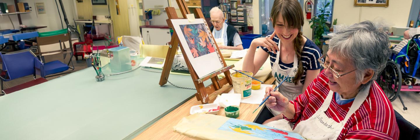 Tenant makes a painting as a nurse smiles and encourages her