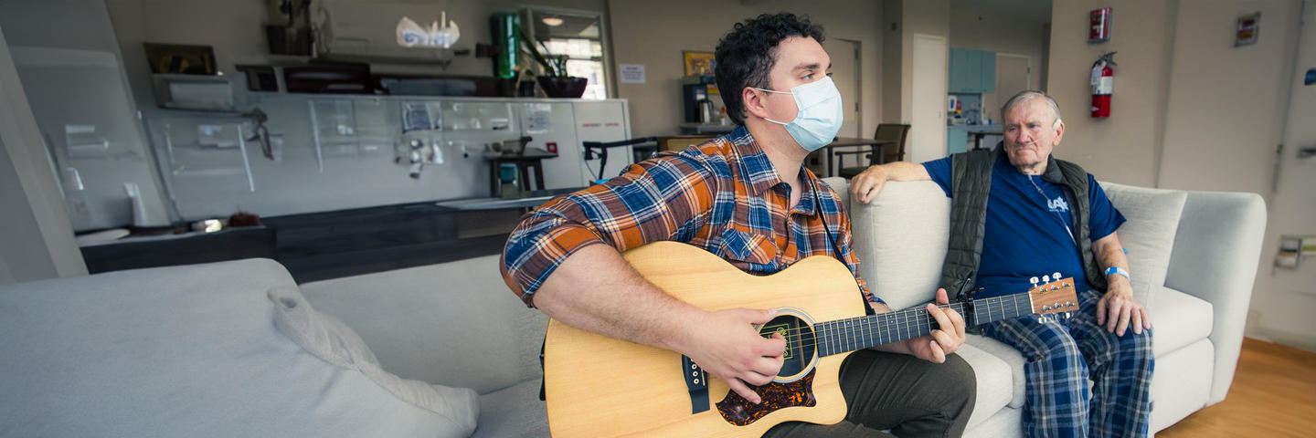 Tenant listens to a music therapist play their guitar