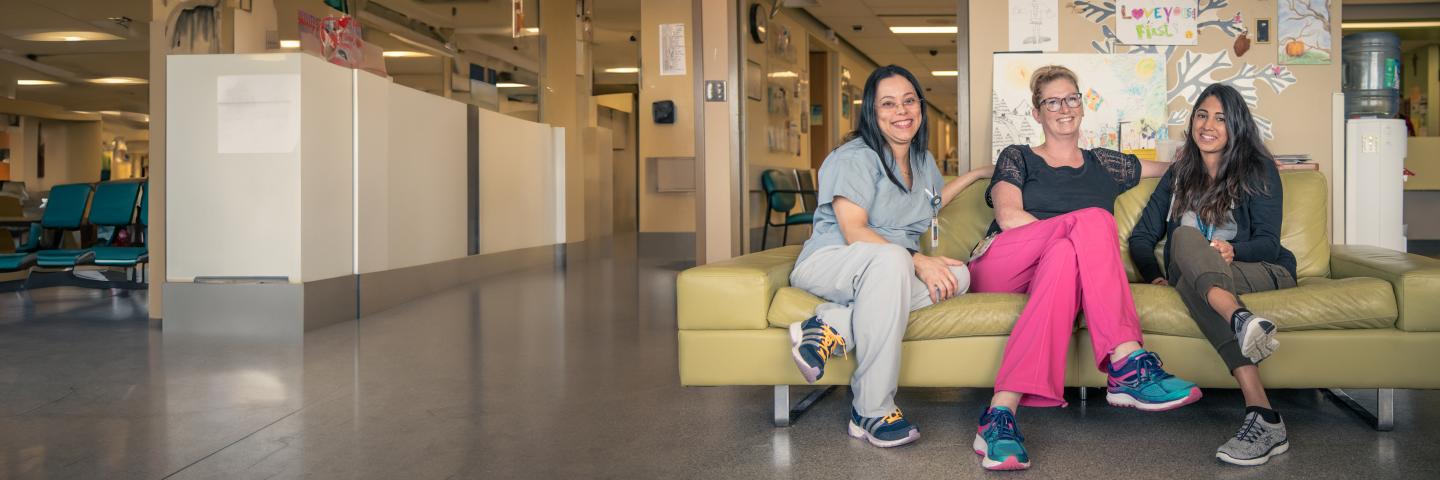 Staff members and a volunteer sitting on a green couch smiling