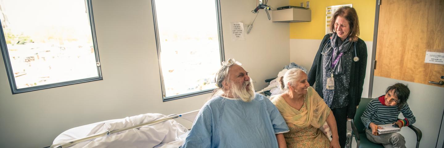 A senior patient, their spouse and grandchild smiling and interacting with a doctor