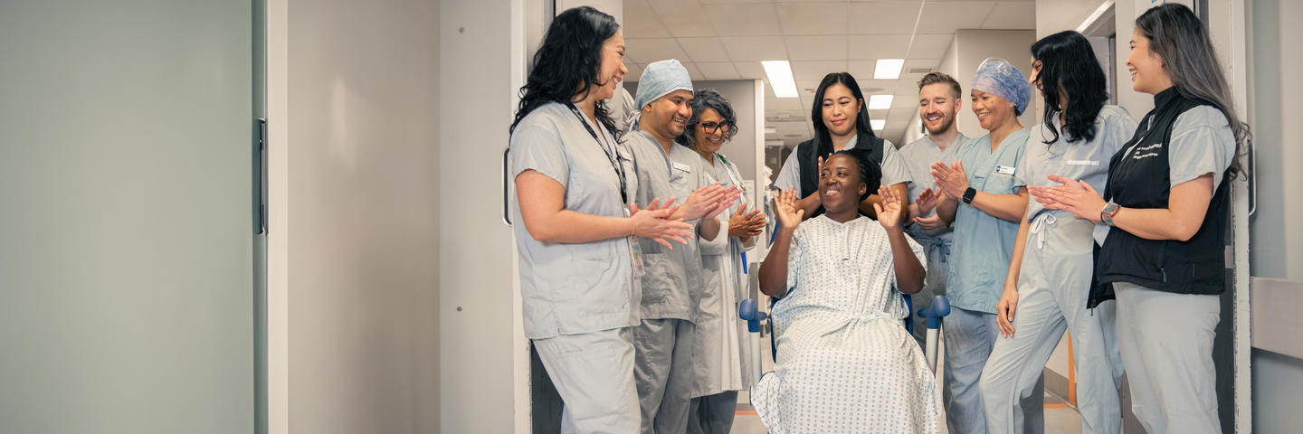 Nurse and doctors cheering a patient in wheelchair.