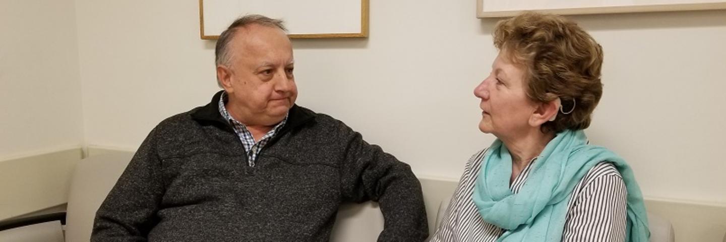 Two people with cochlear implants seated in a waiting room