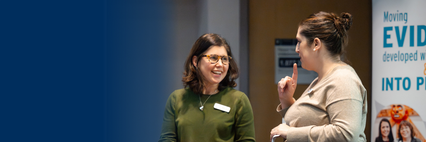 Two women chat at a conference