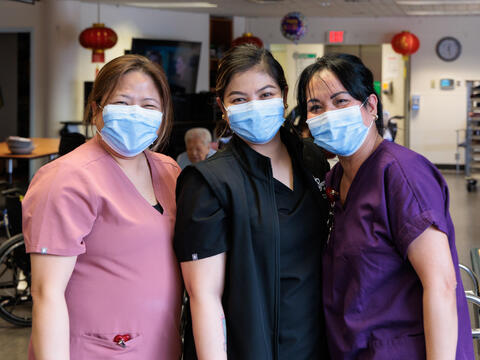 Three nurses wearing pink, black and purple scrubs