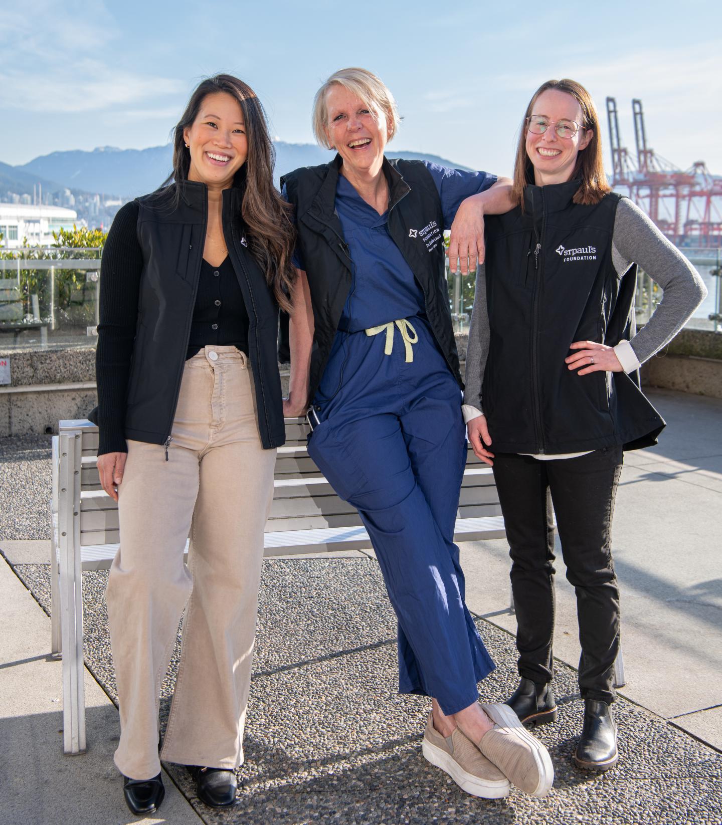 three people wearing hospital clothing smiling outdoors