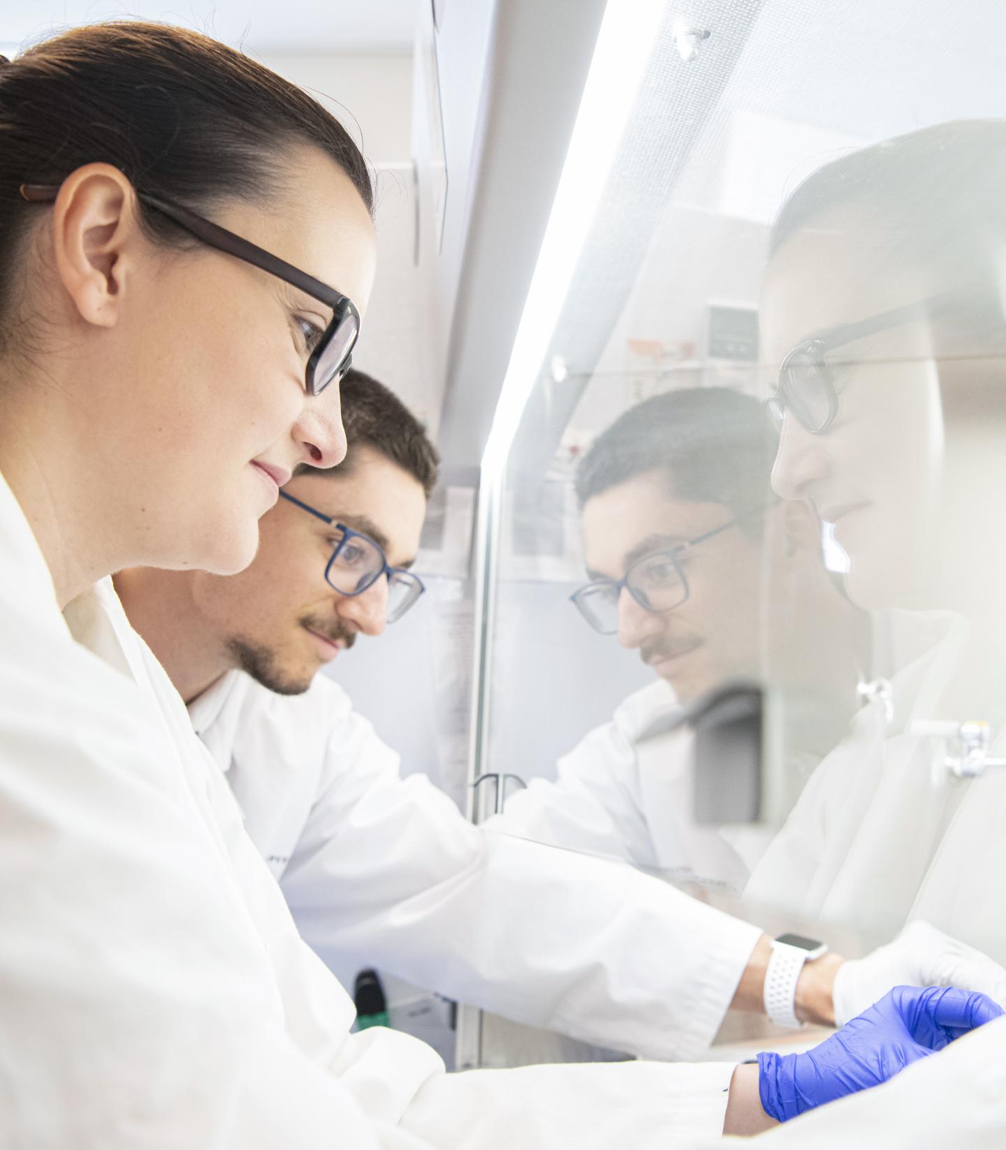 Two scientists in white work in a lab