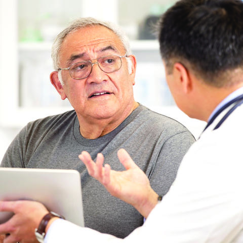 Older man talking with a man holding an tablet