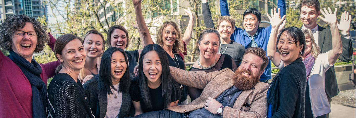 Staff members raising their hands, smiling and being enthusiastic